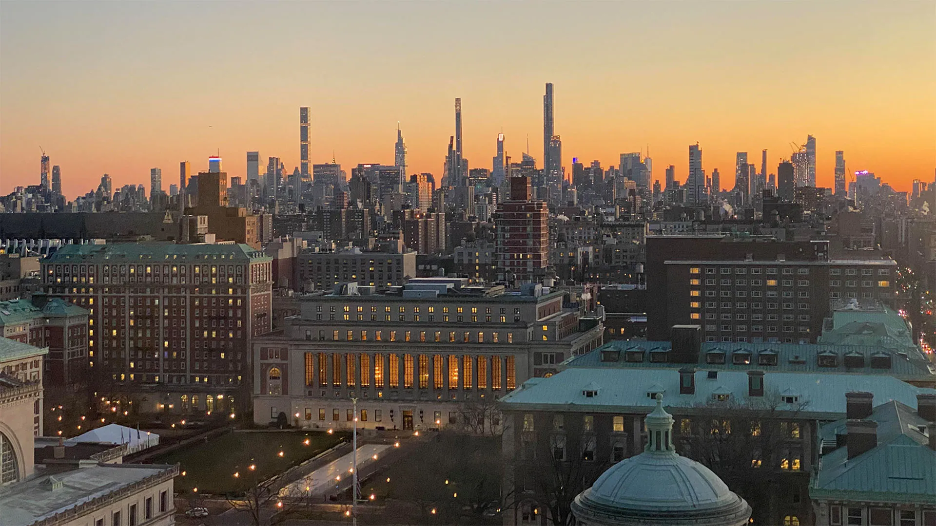 Aerial view of Columbia's campus with the NYC skyline at dusk.